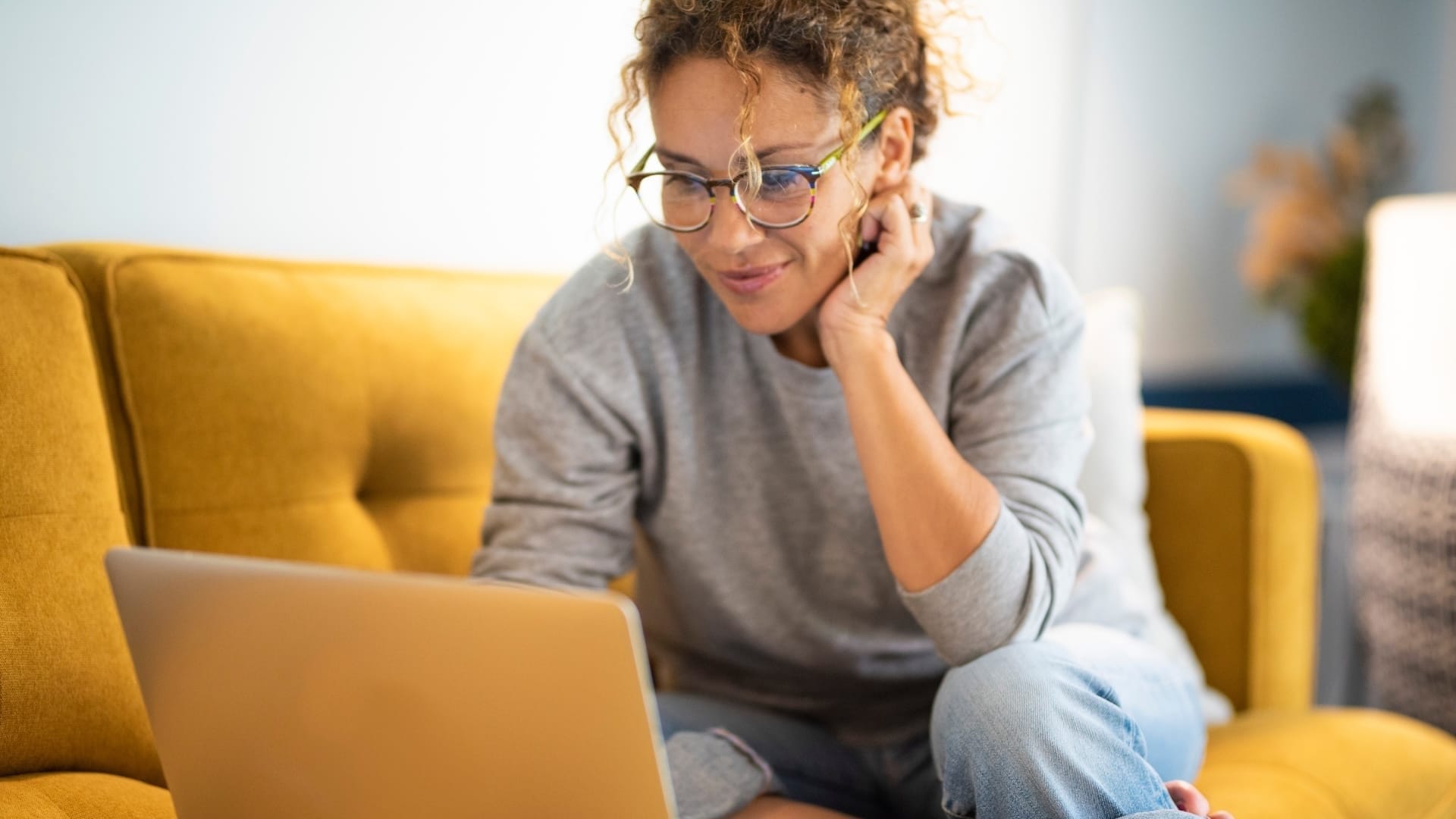 Junge Frau sitzt mit Notebook auf der Couch